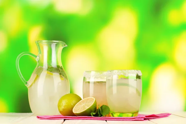 Citrus limonade in werper en bril op houten tafel op natuurlijke achtergrond — Stockfoto