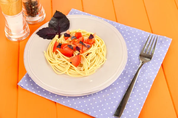 Spaghettis aux tomates et feuilles de basilic sur serviette sur fond bois — Photo