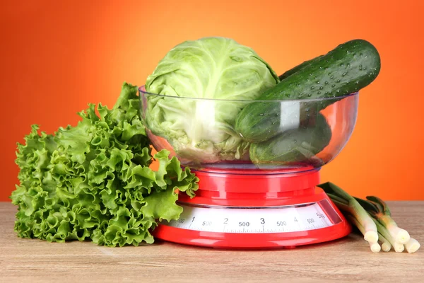 Verse groenten in schalen op tafel op oranje achtergrond — Stockfoto