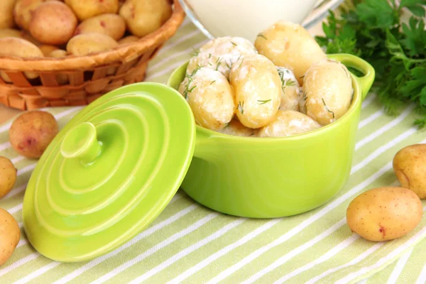 Inschrijving van jonge aardappelen met zure room en kruiden in pan op houten tafel close-up — Stockfoto