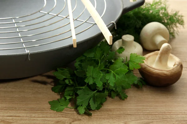 Zwarte wok pan en paddestoelen op houten keukentafel, close-up — Stockfoto