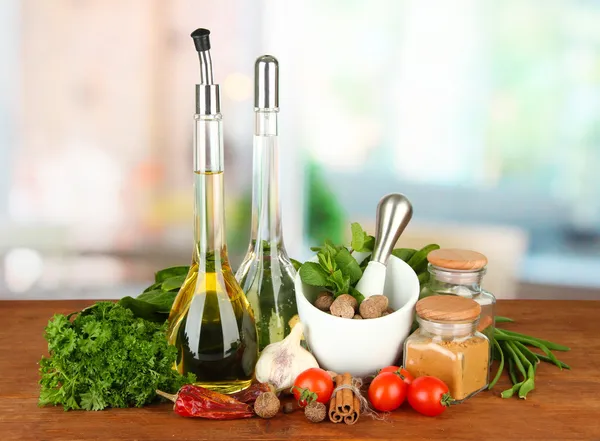 Composition of mortar, bottles with olive oil and vinegar, and green herbals, on bright background — Stock Photo, Image