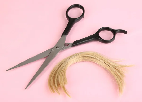 Pedaços de cabelo cortados com tesoura sobre fundo rosa — Fotografia de Stock