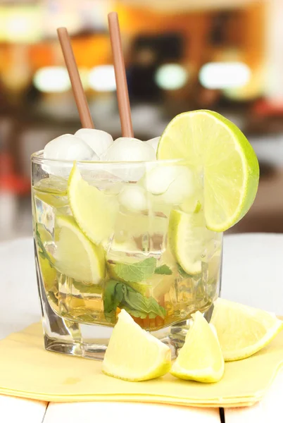 Glass of cocktail with lime and mint on white wooden table on bright background — Stock Photo, Image