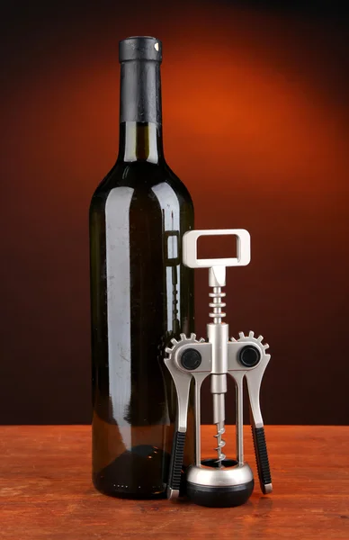Composition of corkscrew and bottle of wine, grape, on wooden table on dark background — Stock Photo, Image
