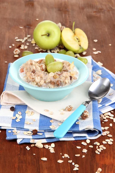 Useful oatmeal in bowl with fruit on wooden table close-up — Stock Photo, Image