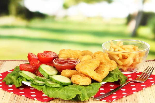 Fried chicken nuggets with french fries,vegetables and sauce on table in park — Stock Photo, Image