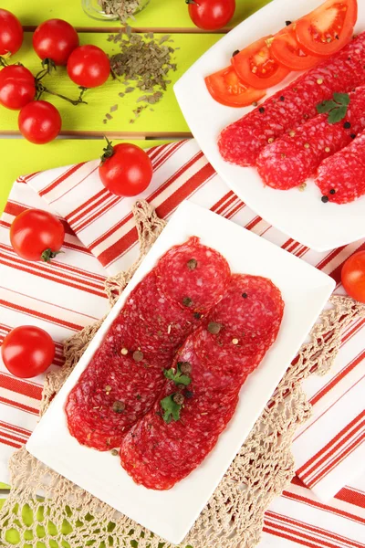 Välsmakande salami på tallrikar på träbord närbild — Stockfoto