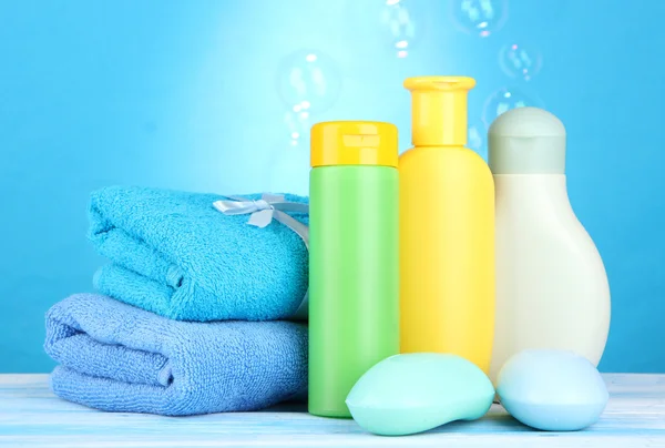 Cosméticos de bebê, toalhas e sabão na mesa de madeira, no fundo azul — Fotografia de Stock