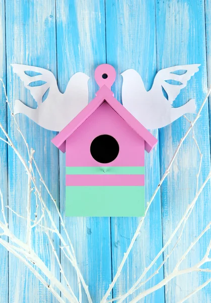 Декоративная коробка для гнездования с бумажными птицами и цветными ветвями, на фоне цвета дерева — стоковое фото