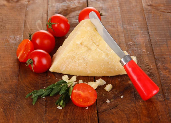 Piece of Parmesan cheese with knife on wooden table close-up — Stock Photo, Image