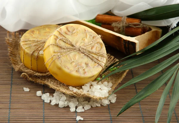 Hand-made soap and sea salt on grey bamboo mat — Stock Photo, Image