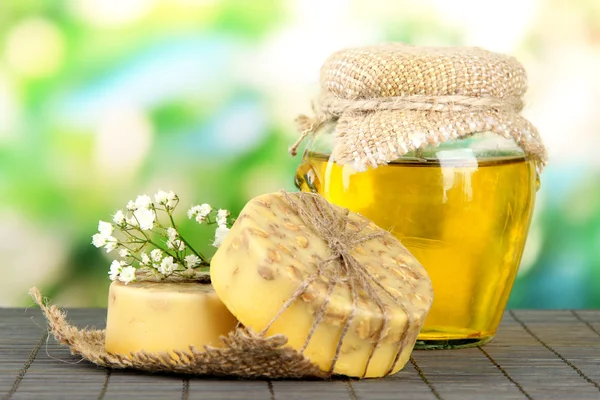Handgemachte Seife und Zutaten für die Seifenherstellung auf Bambusmatte, auf grünem Hintergrund — Stockfoto