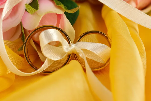 Anillos de boda atados con cinta sobre fondo brillante — Foto de Stock