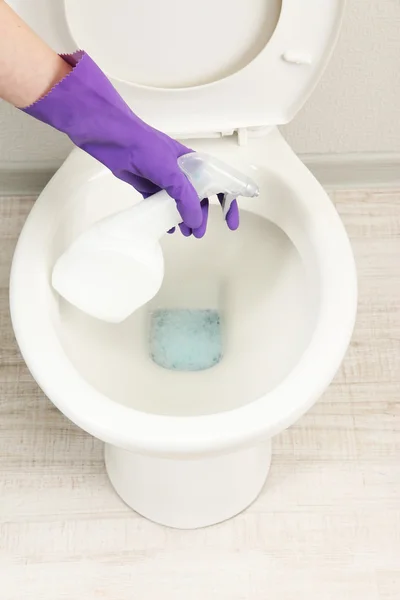 Mano de mujer con botella de spray limpiando un inodoro en un baño —  Fotos de Stock