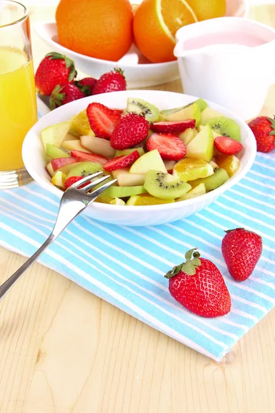 Useful fruit salad of fresh fruits and berries in bowl on napkin on wooden table close-up — Stock Photo, Image