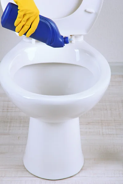 Woman hand with spray bottle cleaning a toilet bowl in a bathroom Stock Picture