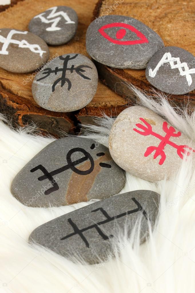 Fortune telling with symbols on stones on white fur background