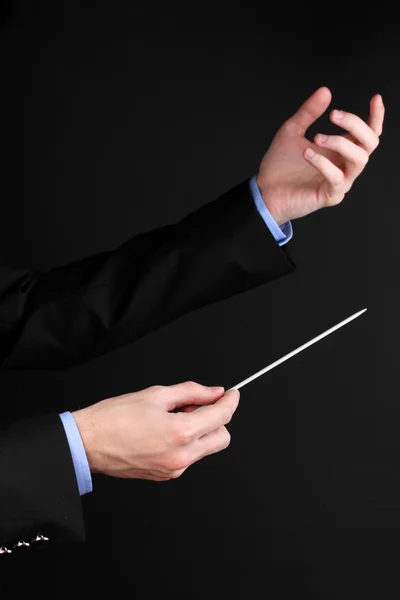 Muziek dirigent handen met stokje geïsoleerd op zwart — Stockfoto