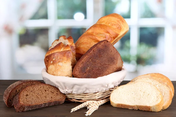 Pane fresco in cesto su tavolo di legno su sfondo finestra — Foto Stock