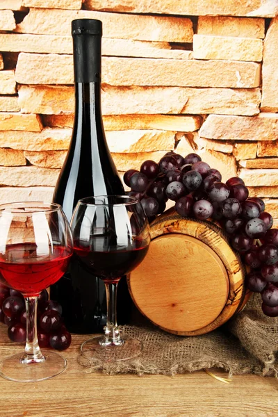 Composição de vinho e uvas em barril de madeira na mesa no fundo da parede de tijolo — Fotografia de Stock