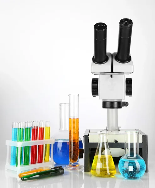 Test tubes with colorful liquids and microscope isolated on white — Stock Photo, Image