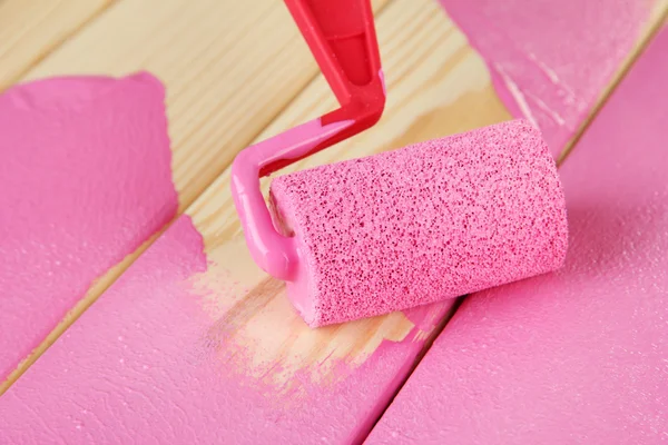 Paint roller brush with pink paint, on wooden background — Stock Photo, Image