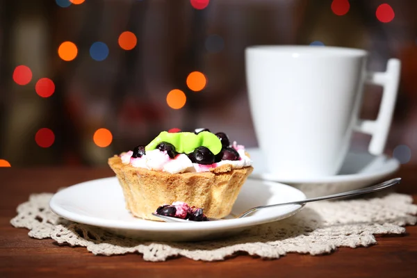 Gâteau de mûres savoureux et tasse de boisson, sur fond sombre avec des lumières bokeh déconcentrées — Photo