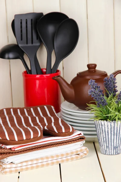 Kitchen settings: utensil, potholders, towels and else on wooden table — Stock Photo, Image