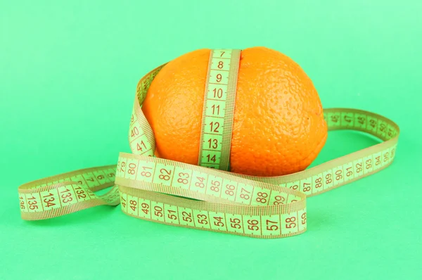 Orange with measuring tape, on color background — Stock Photo, Image