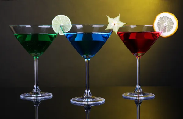 Alkoholische Cocktails in Martinigläsern auf dunkelgelbem Hintergrund — Stockfoto