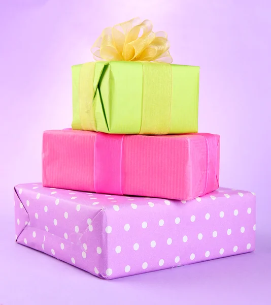 Bright gifts with bows on purple background — Stock Photo, Image