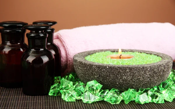 Candle in stone bowl with marine salt, on bamboo mat, on brown background — Stock Photo, Image