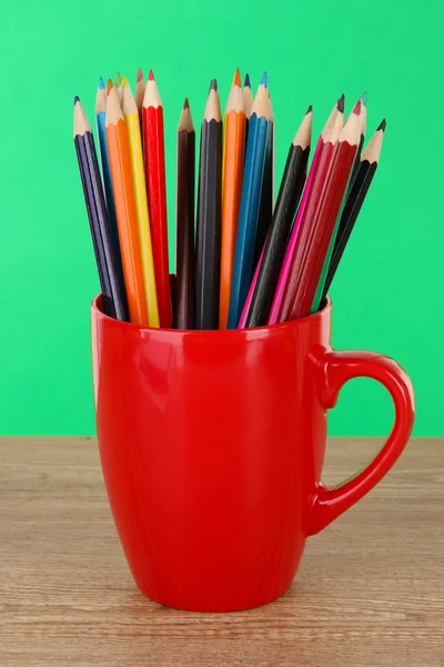 Colorful pencils in cup on table on green background — Stock Photo, Image