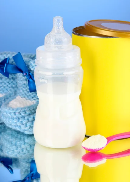 Biberón con leche y comida para bebés sobre fondo azul — Foto de Stock