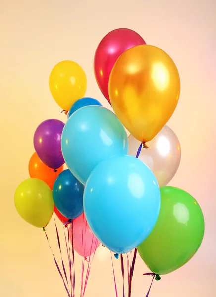 Veel heldere ballonnen op oranje achtergrond — Stockfoto