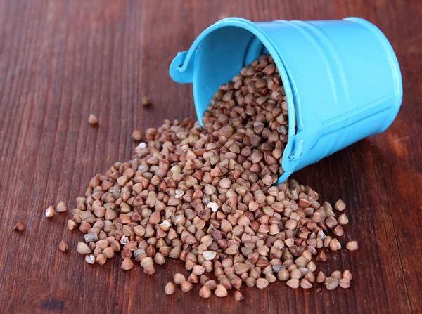 Overturned bucket with grains on wooden background — Stock Photo, Image