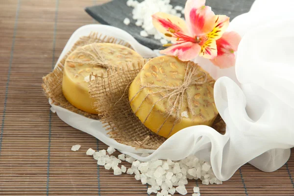 Hand-made soap and sea salt on grey bamboo mat — Stock Photo, Image