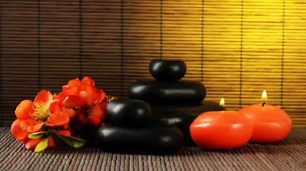 Wellness-Steine mit Blumen und Kerzen auf Bambus-Hintergrund — Stockfoto