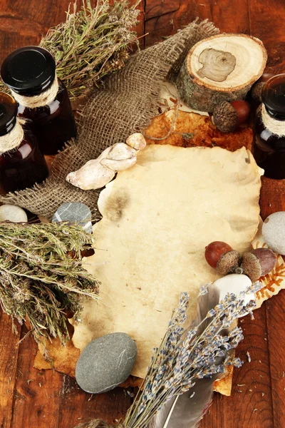 Composition with old papers, herbs, stones and bottles with symbols on wooden background — Stock Photo, Image