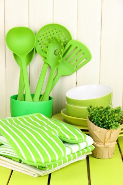 Kitchen settings: utensil, potholders, towels and else on wooden table clipart