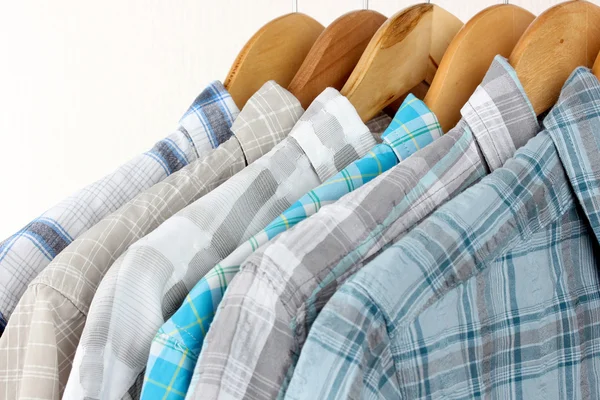 Shirts met banden op houten hangers op lichte achtergrond — Stockfoto