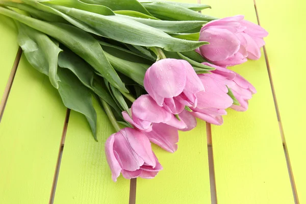 Schöner Strauß lila Tulpen auf grünem Holzhintergrund — Stockfoto