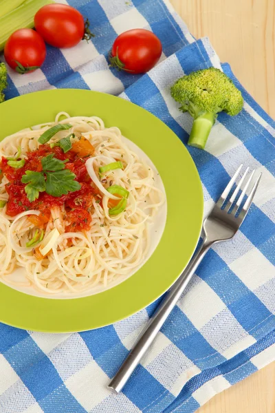 Espaguete saboroso com molho e legumes na placa na mesa de madeira close-up — Fotografia de Stock