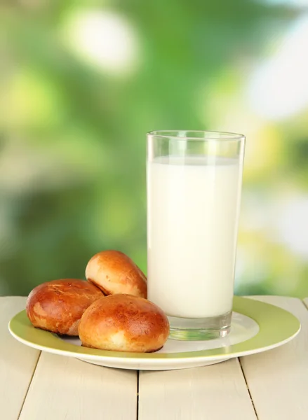 Panini e bicchiere di latte sul tavolo di legno sullo sfondo della natura — Foto Stock