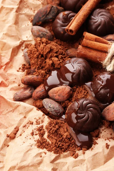 Composition of chocolate sweets, cocoa and spices on brown background — Stock Photo, Image