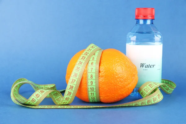 Orange with measuring tape, bottle of water, on color background — Stock Photo, Image