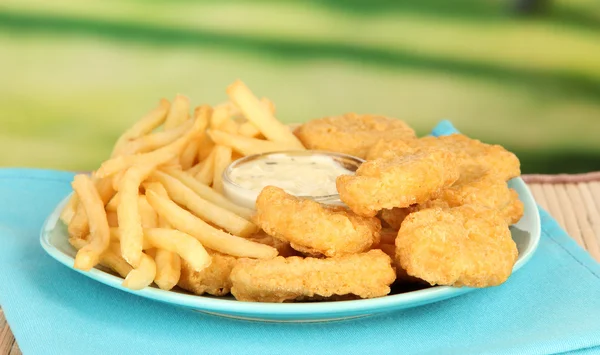 Fried chicken nuggets with french fries and sauce on table in park — Stock Photo, Image