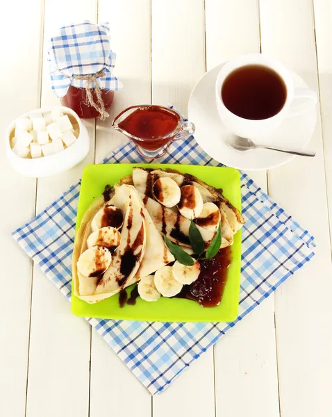 Pancakes with banana on plate on wooden background — Stock Photo, Image