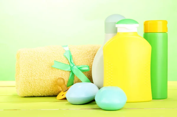 Cosméticos para bebés, jabón y toalla sobre mesa de madera, sobre fondo verde —  Fotos de Stock